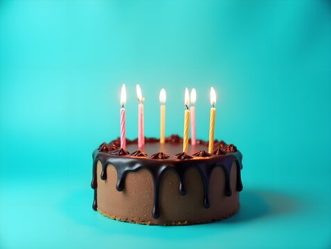 Chocolate birthday cake with lighted candles and chocolate icing on a turquoise background