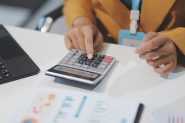 Accountant, Asian independent business woman uses calculator to calculate company financial results on table in office and business work history, tax, accounting, statistics and analytical concepts.