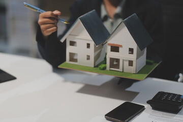 Real estate agents explain models of housing estates in projects to elaborate to clients, explaining and presenting information about homes and purchasing loans. Real estate trading concept.