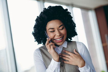 Smiling Successful Businesswoman Engaged in a Lively Phone Call Inside an Office Setting