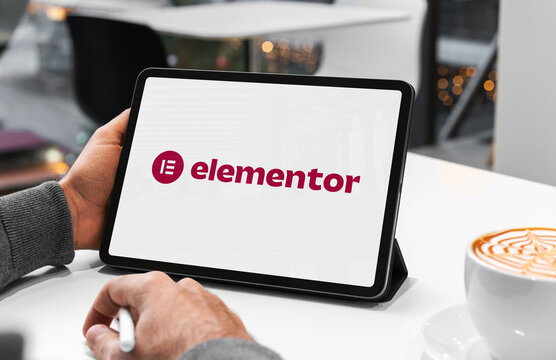 Web designer working with elementor website builder on tablet in cafe