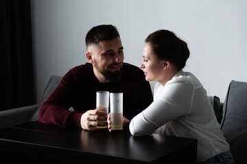 Couple enjoying intimate conversation and drinks together in cozy living space during evening hours...