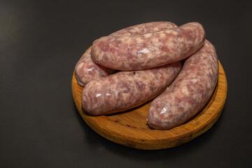 Meat sausages prepared for grill on a wooden board. Raw sausages for grill.