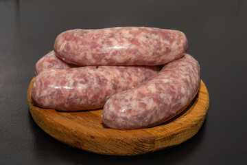 Meat sausages prepared for grill on a wooden board. Raw sausages for grill.