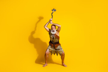 Photo of old barbarian man feel anger raise weapon rock wear animal skin isolated yellow color background