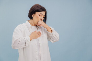 Middle aged woman suffering from cough and chest pain on blue background