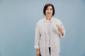 Middle aged woman showing pills blister packs on blue background