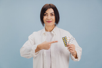 Middle aged woman pointing at blister packs containing different pills