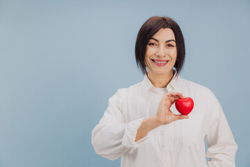 Middle aged woman holding red heart promoting cardiovascular health and disease prevention