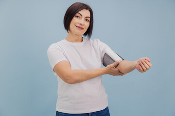 Brunette Woman Measuring Blood Pressure with Electronic Device on Blue Background