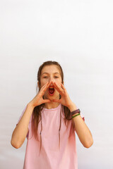 Teenage girl screaming like into a megaphone, holding hands to face with mouth open. Vertical photo on white background.