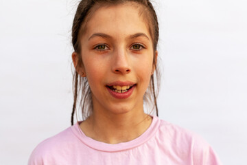 Girl with big smile showing crooked teeth, malocclusion on white background