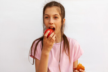 Girl in pink t-shirt holds in one hand delicious croissant and in the other hand red apple on white background. Healthy eating concept