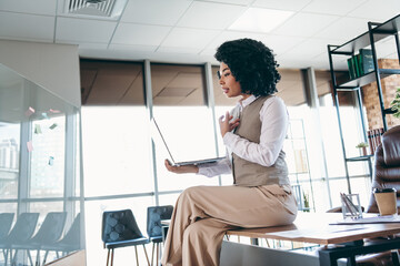 Young professional businesswoman working in modern office setting using laptop technology for video conference