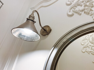 A beautiful lamp is elegantly hanging on a wall right next to a mirror, enhancing the ambiance of...
