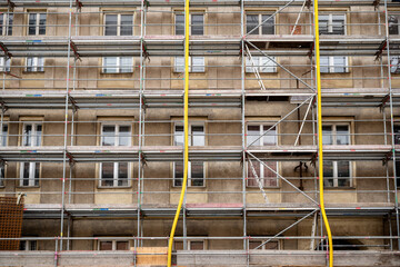 Old residential building facade with metal scaffolding, concept of construction and renovation site