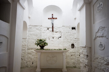 Sacred columbarium with white walls, crucifix, and floral arrangement on an altar in Yazlovets,...