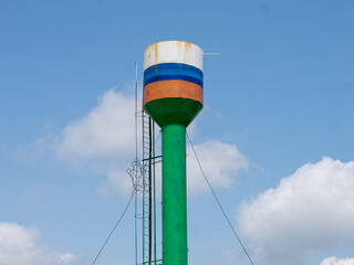A tall green and blue water tower with a ladder on top