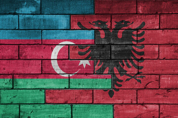 colourful painted big national flag of albania and flag of azerbaijan on a massive old brick wall background. concept