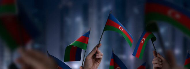 Azerbaijan flags in their hands on a blurred urban background