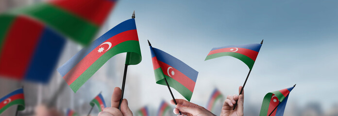 Azerbaijan flags in their hands on a blurred urban background