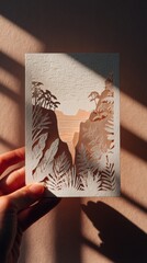 Embracing Life's Curves: Hand holding card with intricate papercut artwork of resilient sea arches at dusk