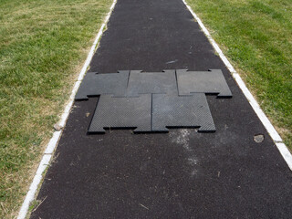 A black mat is laying on the ground in a grassy area