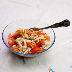 Ciotola di vetro con insalata di pollo con pomodori e sottaceti