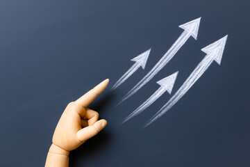 Hand with finger pointing towards upward arrows drawn with chalk dark background, symbolizing growth and strategy business. image evokes feelings of progress and success strategic planning