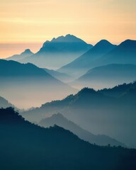 Fototapeta premium Layered mountain ranges fade into mist under a soft dawn sky, with silhouetted peaks and lush slopes. The serene, atmospheric landscape captures nature’s tranquil beauty and depth.