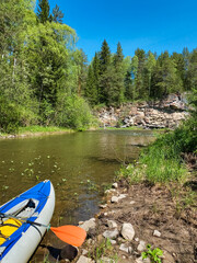 Two colorful kayaks are peacefully resting on the sandy shore of a beautiful river, waiting for their adventurous riders to take them for a thrilling ride on the water surface