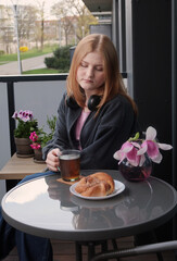sad teenager girl with bun and cup of tea on balcony