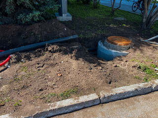 A manhole cover is being installed by the roadside for access to essential underground utilities and drainage systems vital for infrastructure maintenance and improvement