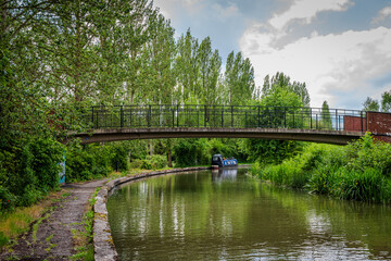A small bridge arches over the Grand Union Canal in Milton Keynes, surrounded by lush greenery 
