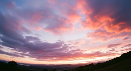 Vibrant Sunset Sky Over Distant City Lights and Rolling Hills