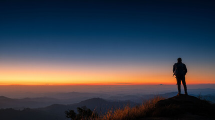 A traveler standing on a hilltop looking at sunrise, captured from behind, clear sky