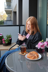 beautiful teenager girl  with smartphone and cup of tea on balcony