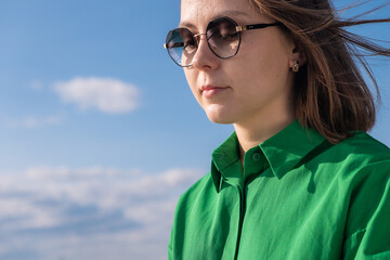 A girl in sunglasses and a green shirt stands on a Norwegian street. Nearby, a young man in sunglasses — a stylish duo caught in a casual city moment.