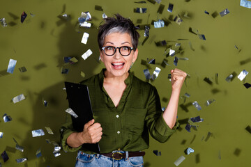 Cheerful Stylish Mature Woman Celebrating Success Over Green Background in Casual Elegance and Dynamic Enthusiasm