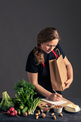 A woman in a black apron slicing tofu on a wooden cutting board. This image represents healthy eating, plant-based cooking, vegetarian lifestyle, and food preparation with organic ingredients.
