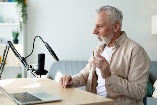Senior man recording podcast using laptop and microphone at home
