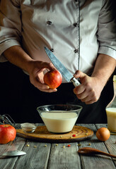 A chef skillfully handles an apple with a knife while preparing dessert. A glass bowl of cream and eggs is nearby along with kitchen utensils, creating a warm atmosphere