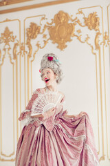 Fototapeta premium Elegant woman in a luxurious Victorian gown joyfully poses indoors, capturing the essence of historical aristocracy, vertical photo