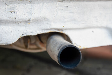 Close-up view of a vehicle's exhaust pipe exhibiting signs of damage. The setting highlights...