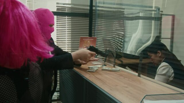 Female bank worker hurrying to give out money in cash to nervous male robber while criminal accidently dropped gun on counter then teller picking up pistol defending herself against two criminals