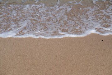 Beige sandy beach and sea waves with foams. Exotic sand beach with copy space
