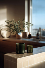 Set of green drinking glasses on natural stone kitchen counter with modern shelving and warm ambient light