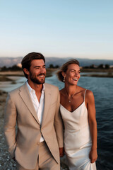 Romantic couple walking by the sea in warm sunset light, elegant summer vacation lifestyle
