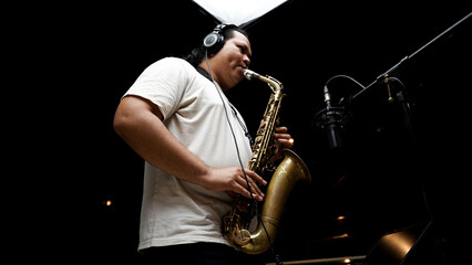 Musician Playing Saxophone in Recording Studio on dark black isolated background