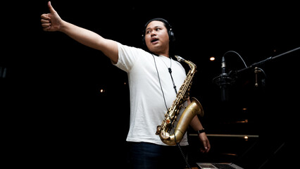 Musician Playing Saxophone in Recording Studio on dark black isolated background
